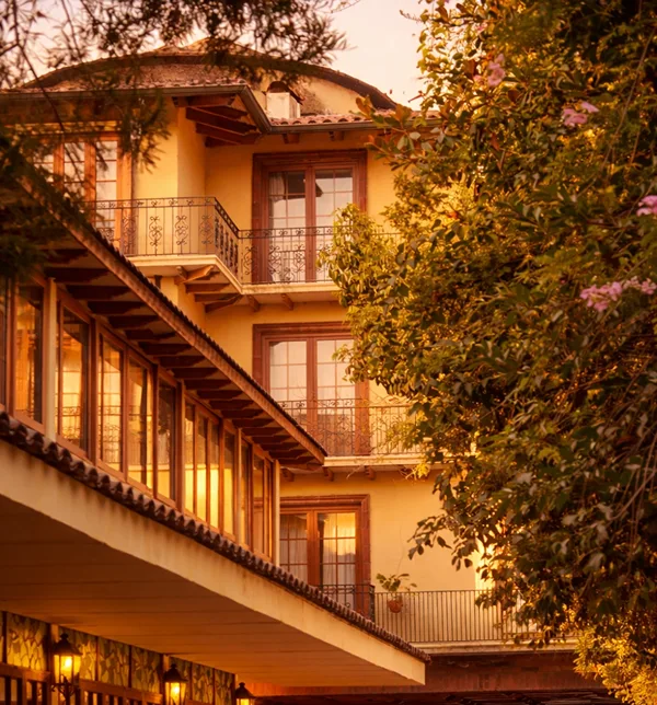 Vista exterior del Hotel Santa Cruz Plaza al atardecer, con arquitectura de estilo colonial, balcones y jardines, ubicado en el corazón del Valle de Colchagua, Chile.