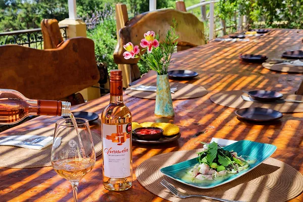 Mesa al aire libre con vino rosado del Valle de Colchagua y un plato de cocina de autor en el Restaurante LOLÓ Cocina de Origen, en Santa Cruz, Chile.
